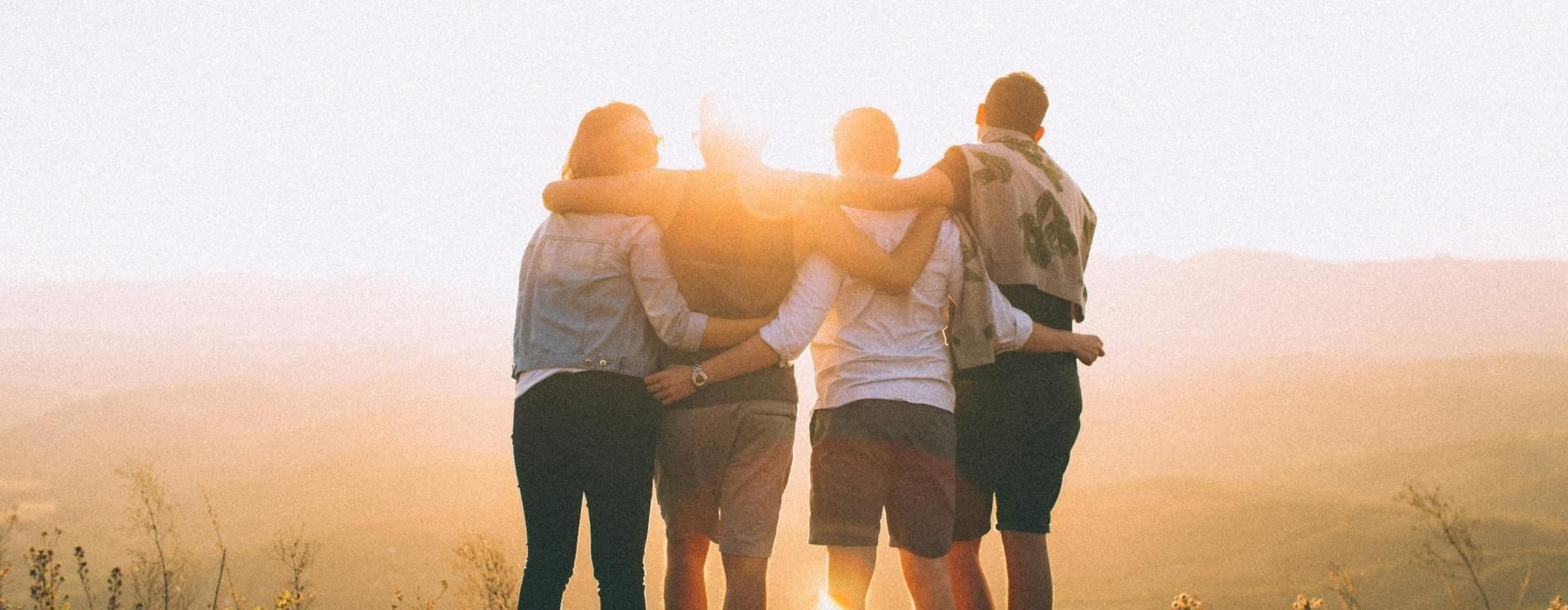 a group of people standing on a hill with their arms around each other